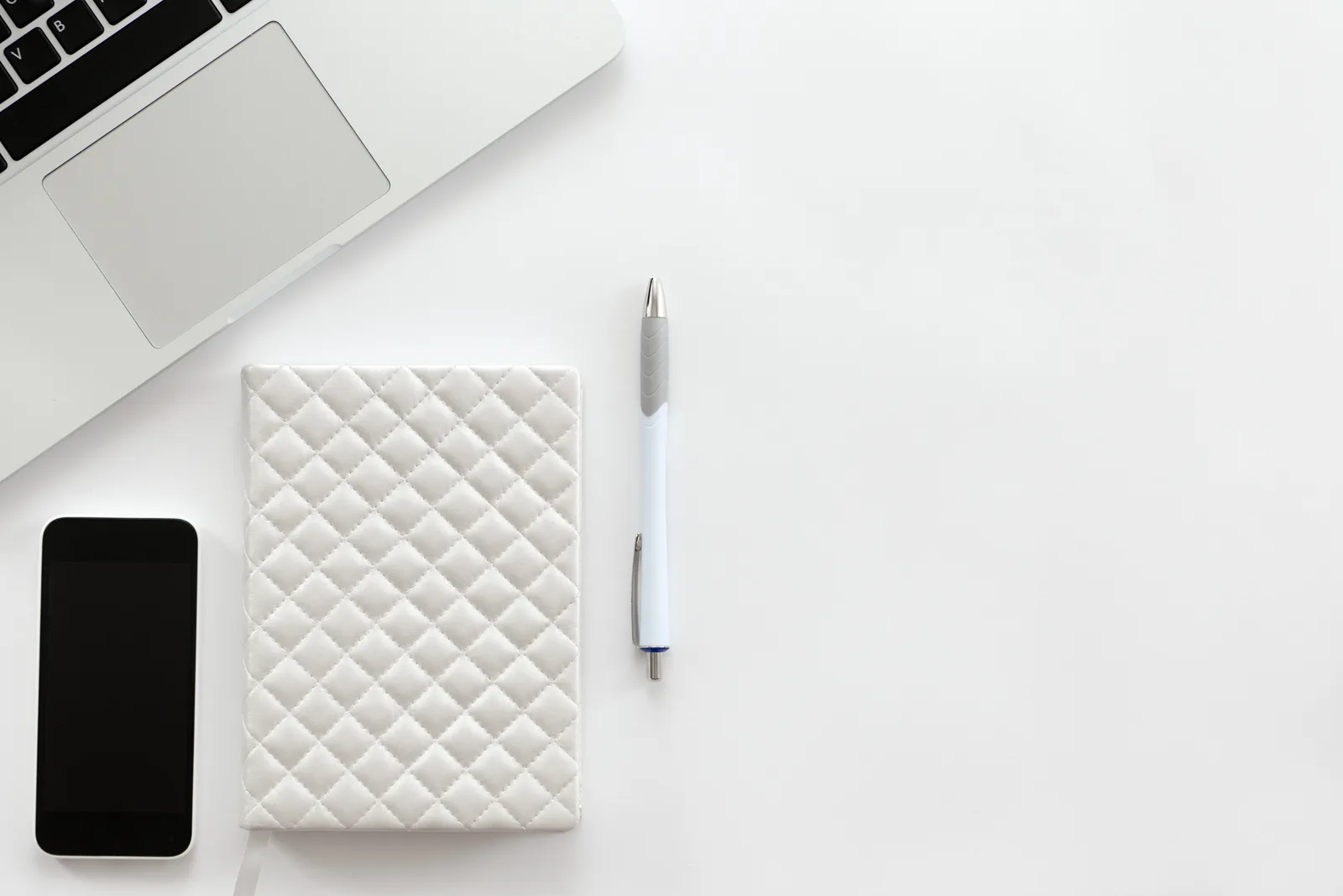 Escritorio minimalista blanco con laptop y smartphone — Le Web Studio, creación de páginas web multilingües para el turismo mexicano